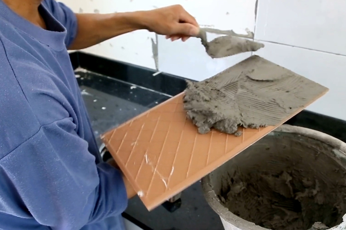 osoba lepi lepak na pločice