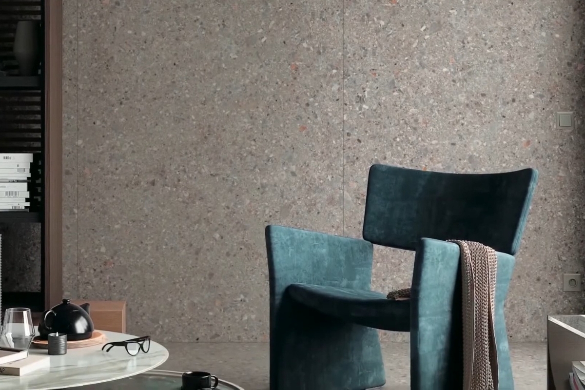 prikaz sivih pločica na zidu u dnevnom boravku, zelena fotelja u prvom planu i pored stolčić na kom su sitnice